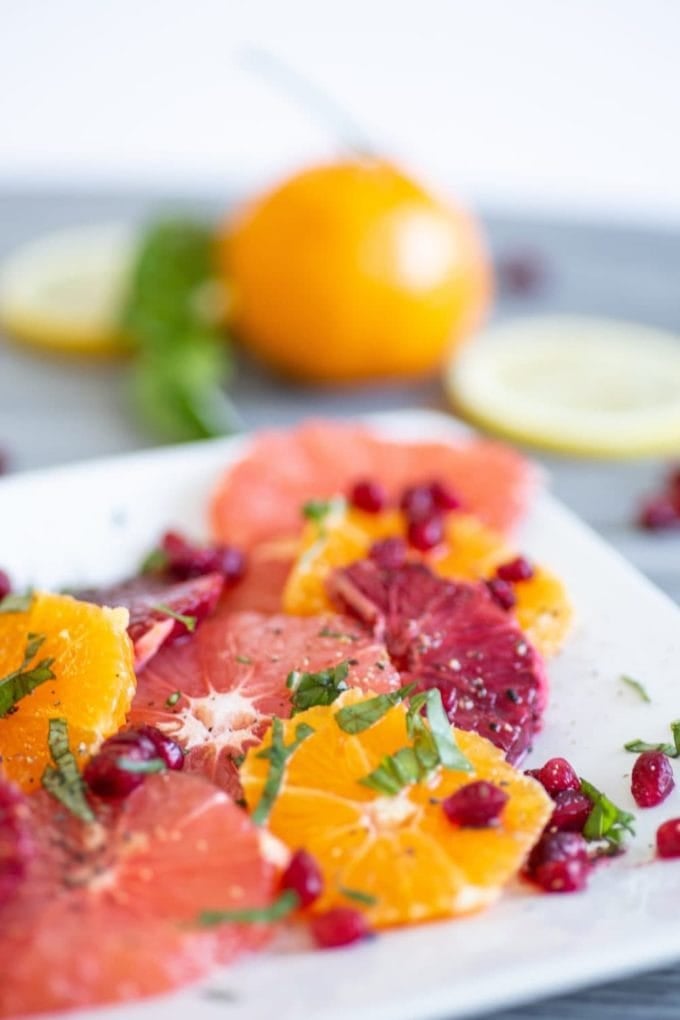 citrus salad on white plate with pomegranate arils