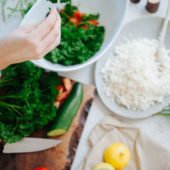 hands preparing parsley over bowls with cauliflower, lemons and tomato