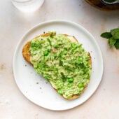 smashed pea toast on white plate with water