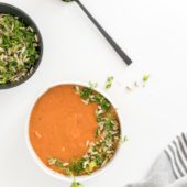 white bowl with tomato soup with spoon and brown bowl of gremolata