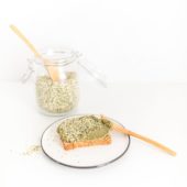 A jar of hemp seeds beside a piece of toast spread with seed butter
