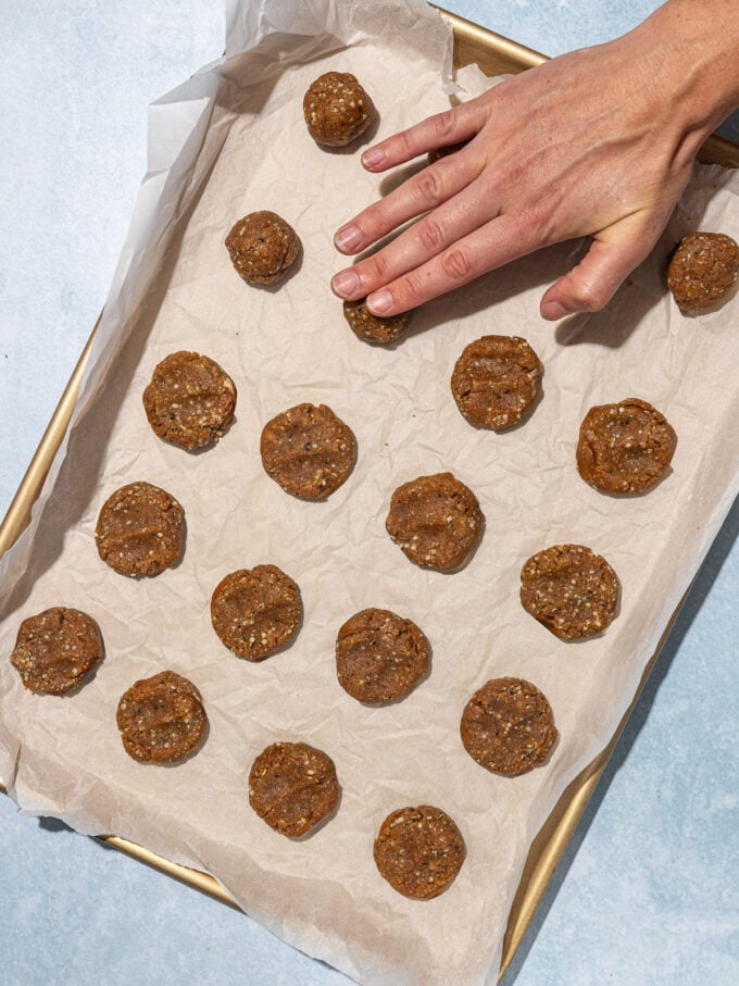 hand pressing raw peanut butter hemp cookies on baking sheet