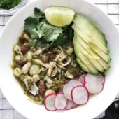 jackfruit and bean soup in white bowl with avocado, radishes and lime