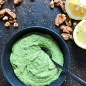 cilantro and parsley pesto in black bowl with walnuts and almonds