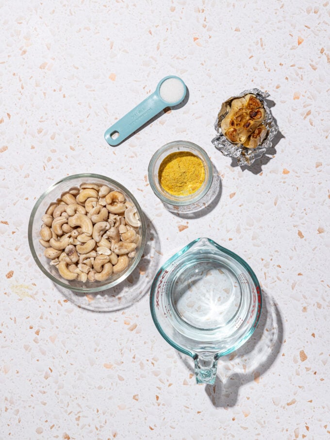 bowls of cashews, nutritional yeast, water with salt and garlic