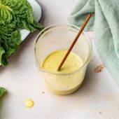 caesar salad dressing in glass jar with lettuce