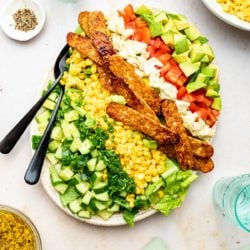 cobb salad with serving spoons and water glass