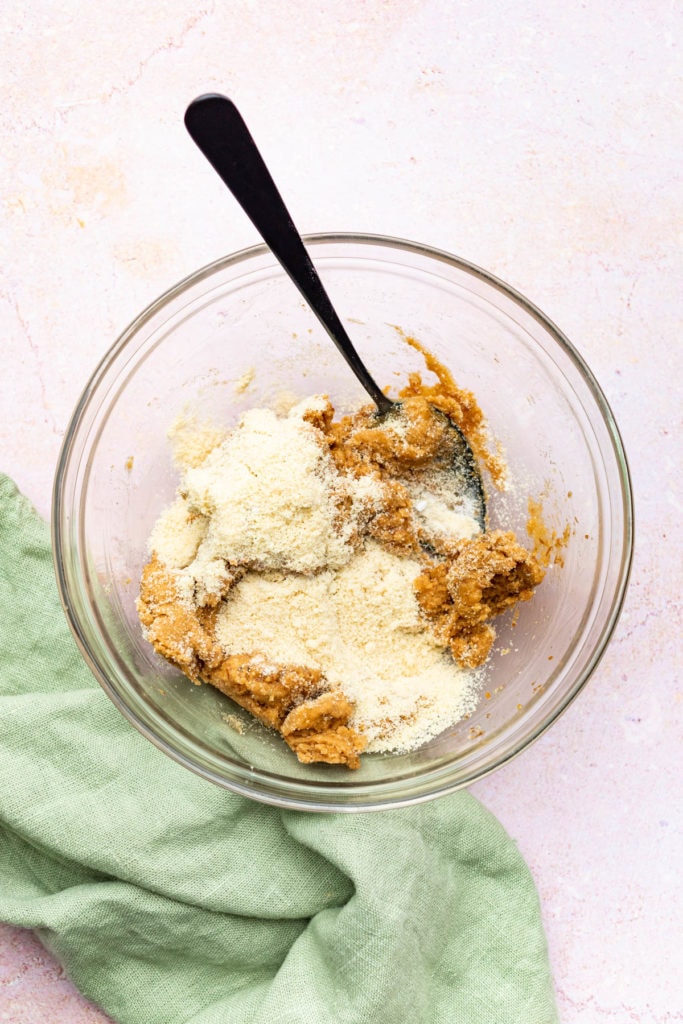 glass bowl with peanut butter cookie ingredients and black spoon