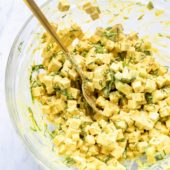 tofu egg salad in glass bowl with gold spoon