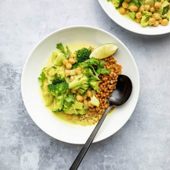 chickpea coconut milk curry in white bowl with spoon and lime