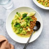 bowl of chickpea coconut milk curry with wheat berries and black spoon
