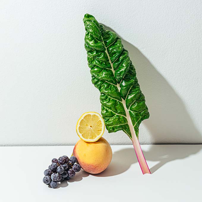 chard leaf with cut lemon, peach and grapes