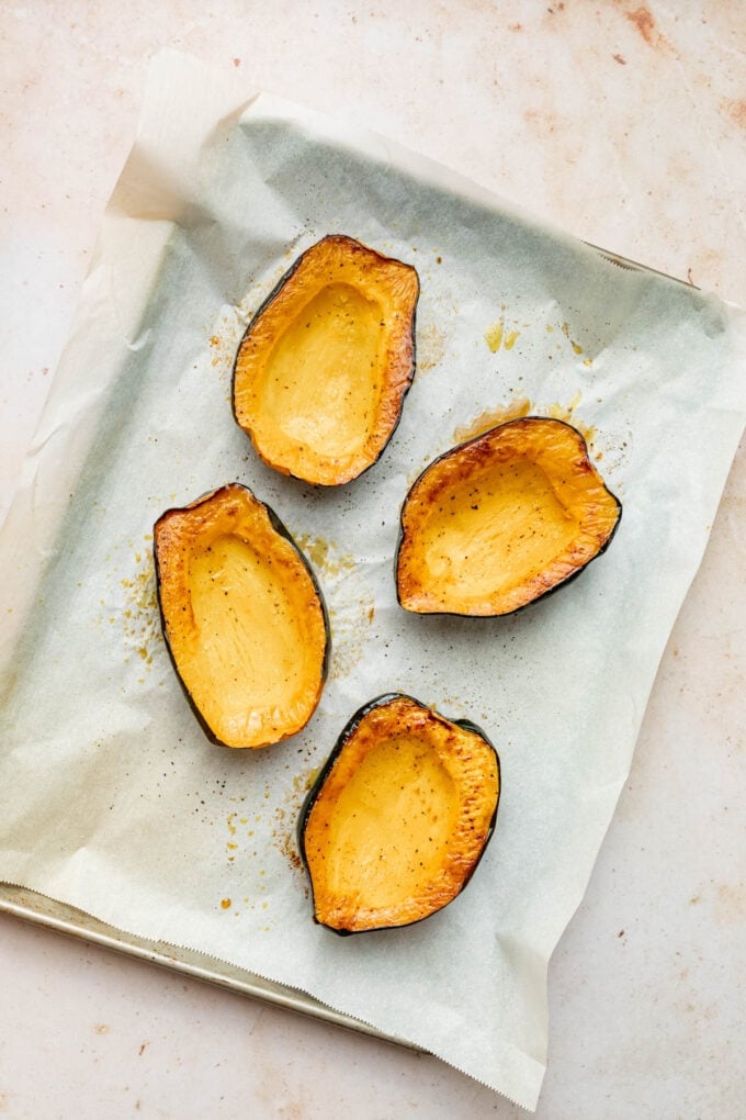 stuffed acorn squash on a baking sheet