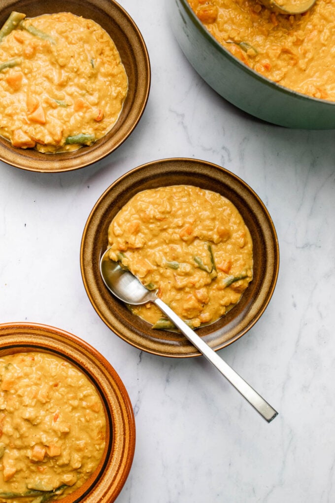 curried lentil tomato coconut soup in bowls with spoon