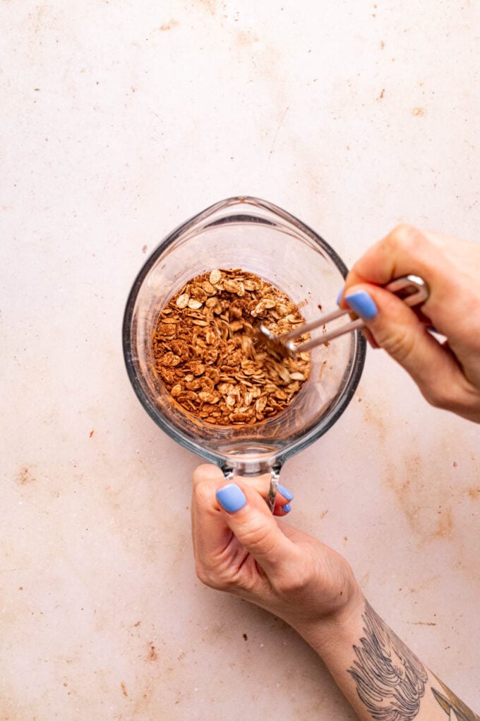 hand stirring oats in jar