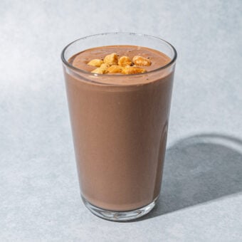 snickers smoothie in glass with peanuts on top
