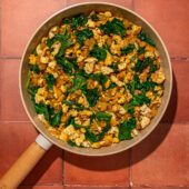 tofu, spinach and potatoes in a skillet on red brick
