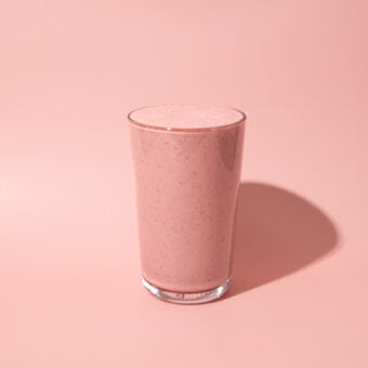 pink smoothie glass against a pink background