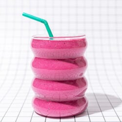 pink smoothie with green straw on black and white tiles