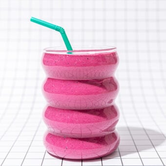 pink smoothie with green straw on black and white tiles