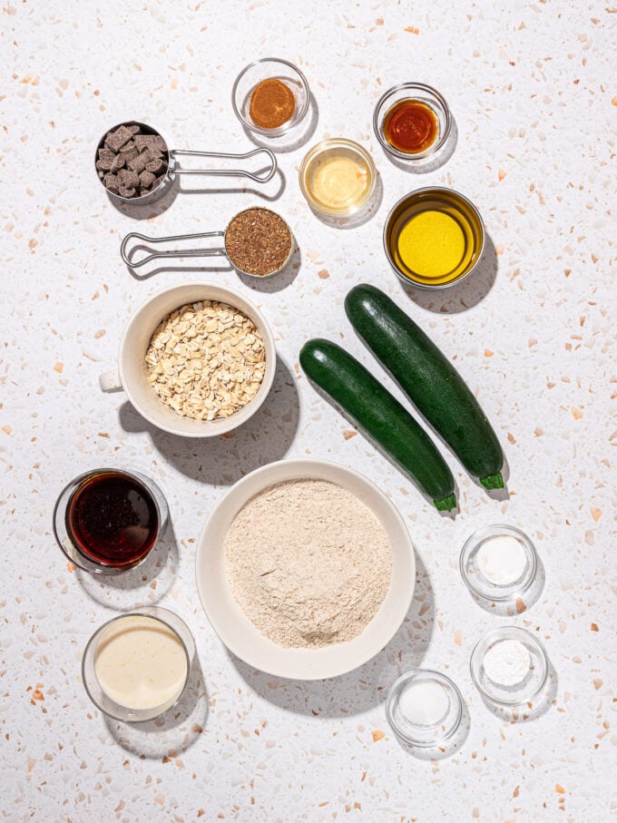 two zucchinis, bowls of flour and oats and spices