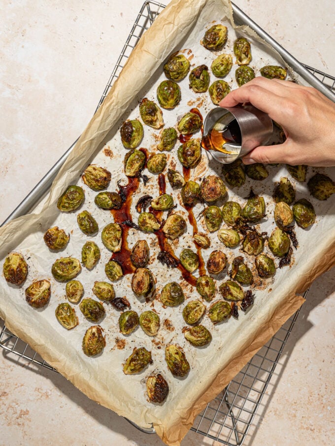 hand pouring maple syrup on roasted brussels sprouts