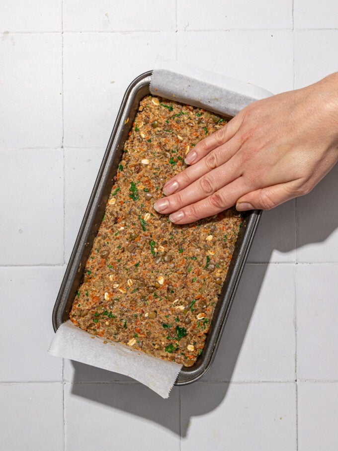 hand pressing vegan meatloaf in pan