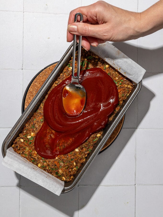 hand spreading glaze on meatloaf in pan