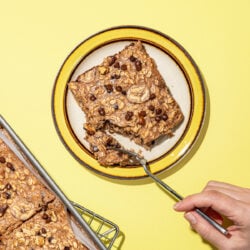 hand cutting piece of banana baked oats with fork on yellow rimmed plate