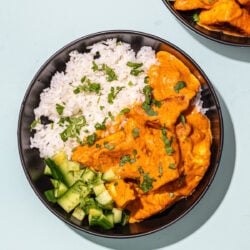 tofu with a sauce, white rice and cucumber in a black bowl