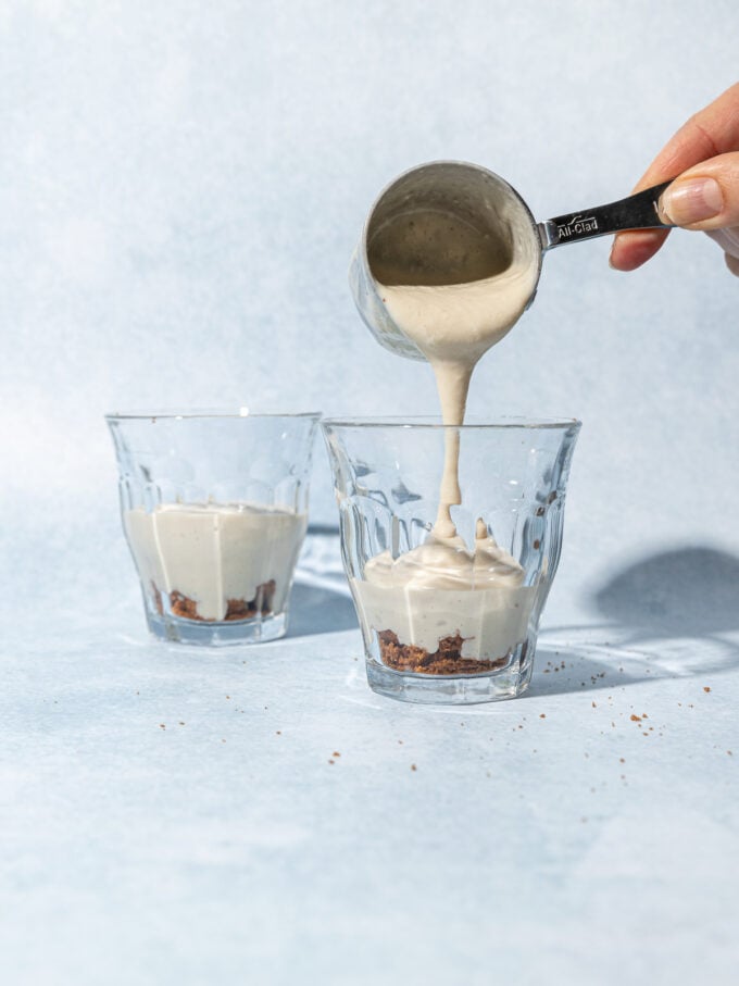 hand pouring pudding into dessert glasses