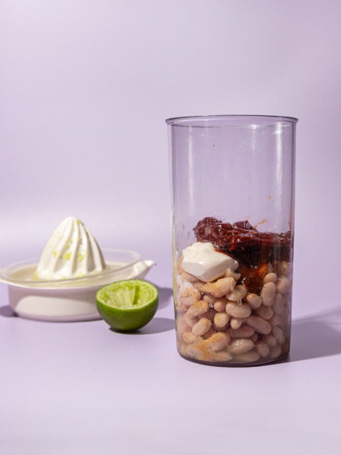 cup of white beans and chipotle peppers beside lime and juicer