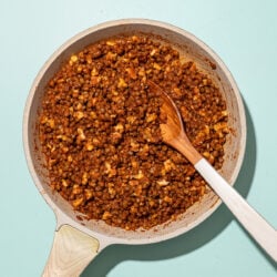 beige skillet filled with lentil walnut taco meat and wooden spoon