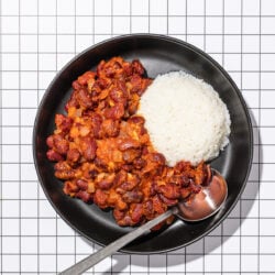 saucy kidney beans with white rice in black bowl with spoon