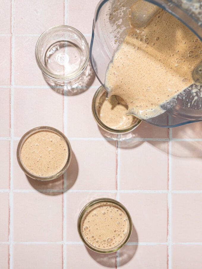 pouring blended chia pudding out of blender into glass jars