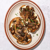 mushrooms on 2 slices of toast on a brown rimmed oblong plate