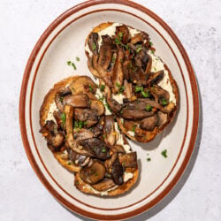 mushrooms on 2 slices of toast on a brown rimmed oblong plate