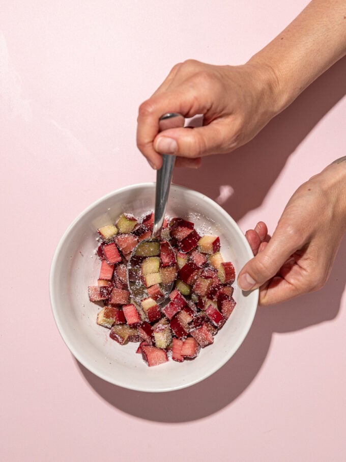 hand stirring rhubarb in white bowl