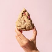 hand holding rhubarb scone in front of pink wall