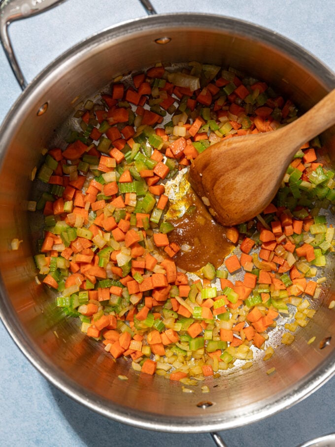 wooden spoon stirring bouillon concentrate in a pot of diced soup veggies