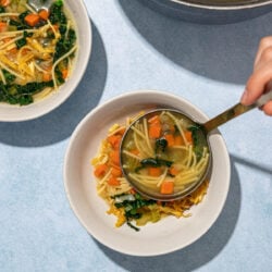 ladling tofu chicken noodle soup into a white bowl