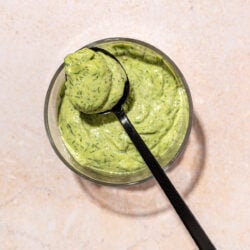 Green goddess dressing in glass bowl with black spoon resting on top