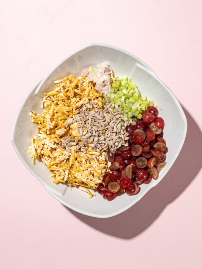 Un bol de tofu cuit au four, graines de tournesol, dés de céleri, tranches de raisins rouges et sauce mayonnaise