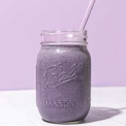 blueberry chickpea smoothie in mason jar with lavender coloured straw