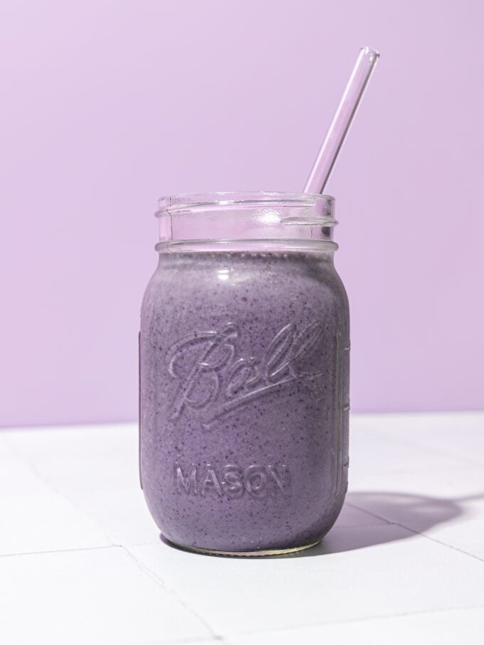 blueberry chickpea smoothie in mason jar with lavender coloured straw