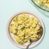 white plate topped with vegan potato salad, with a spoon.