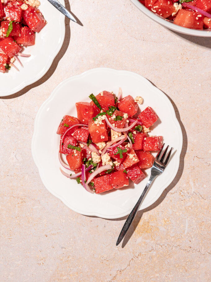 white plates topped with watermelon mint salad with a fork resting beside it