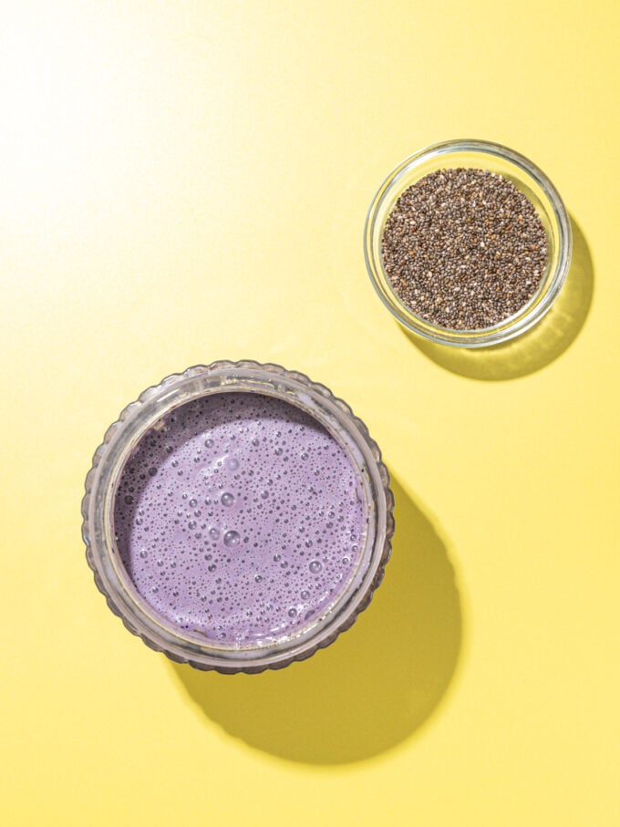 blended lemon blueberry milk in a jar with a dish of chia seeds beside it