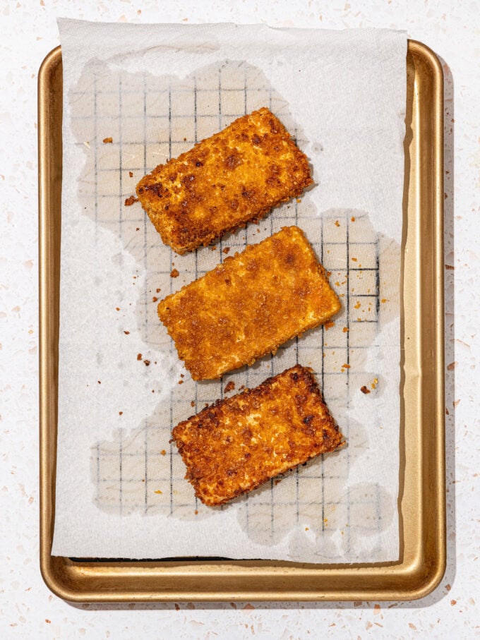 cornflake crusted tofu cutlets draining on a paper towel lined wire rack