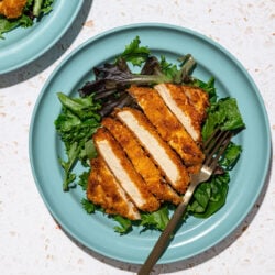 sliced tofu cutlets with salad on blue plates and a black fork